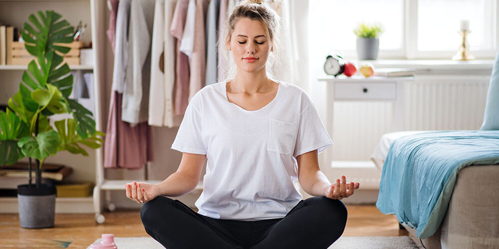 Young woman doing yoga exercise indoors at home, meditating.